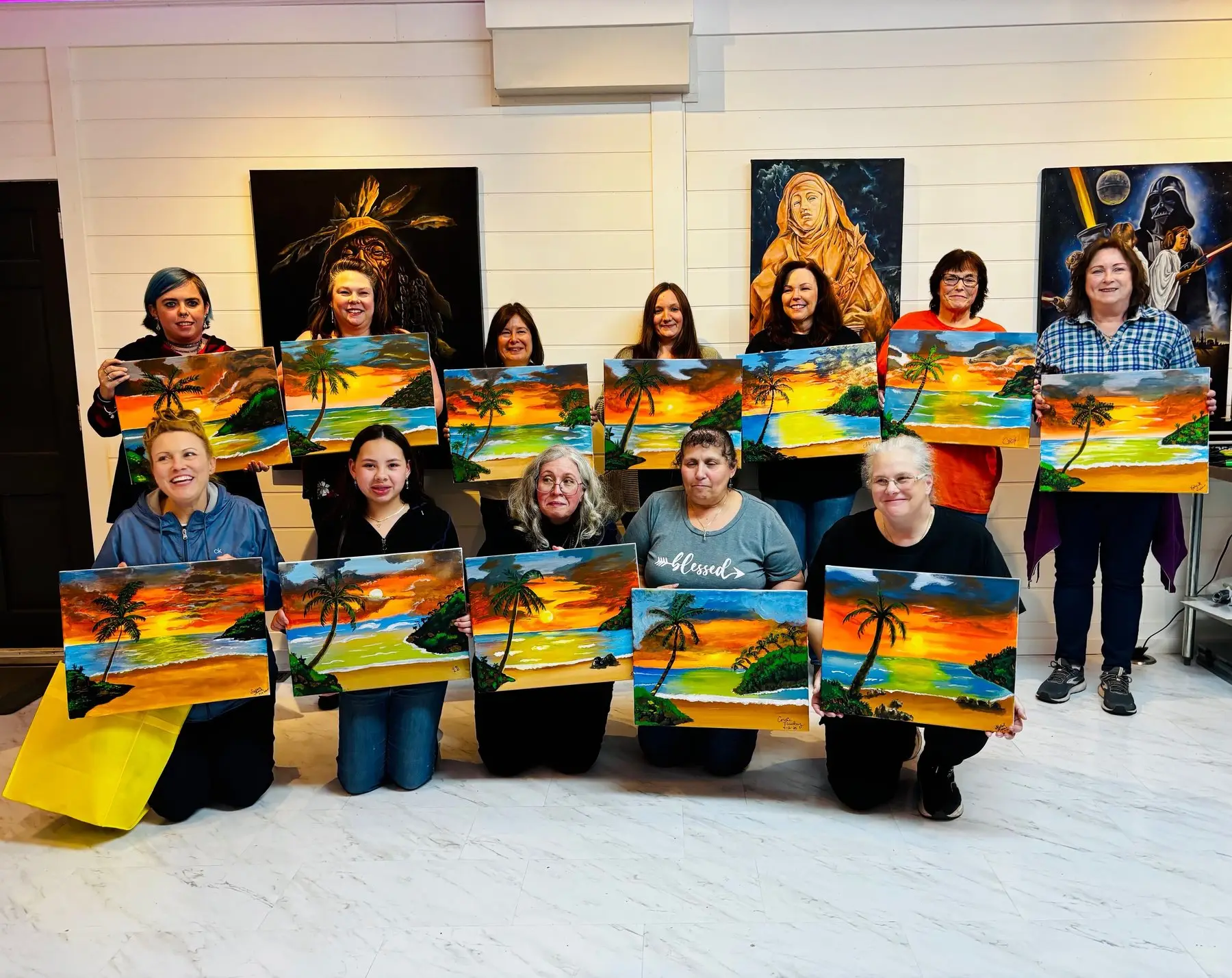Paint night group showing their finished canvases