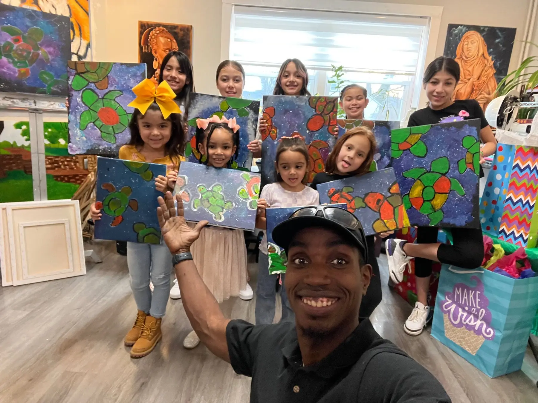 Kids holding up their paintings with Jean Esther